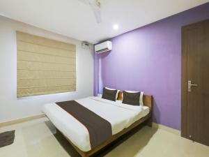 a bedroom with a bed with a purple wall at Collection O Nirvana Lodge in Guwahati
