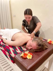 kobieta dająca kobiecie masaż na łóżku w obiekcie Mirah Guest House w mieście Tampaksiring