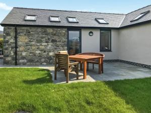 a patio with a wooden table and two chairs at Beudy Wern Goch in Llanuwchllyn
