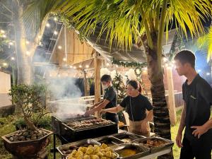 un gruppo di persone che cucinano cibo su una griglia di Komleo Farm a Buôn Kô M'lêo