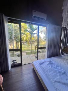 a bedroom with a bed and a sliding glass door at Komleo Farm in Buôn Kô M'lêo