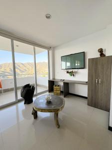 a living room with a table and a tv at Hotel TNT Mirador in Taganga