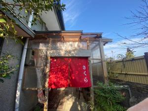 una manta roja está colgando en el costado de una casa en ゲストハウス アルベルゲ Guesthouse ALBERGUE SAKURA, en Sukumo