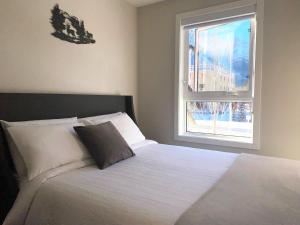 a bedroom with a white bed with a window at Mountain Retreat: Brand New 2BR Condo in Canmore