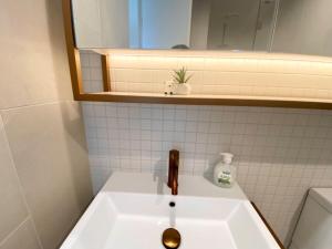 een wastafel in de badkamer met een kraan en een spiegel bij Galleria Deluxe & Spacious apartment + Shopping Centre & Train in Glen Waverley