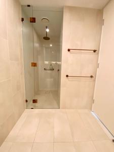 een douche met een glazen deur in de badkamer bij Galleria Deluxe & Spacious apartment + Shopping Centre & Train in Glen Waverley