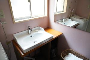uma casa de banho com um lavatório branco e um espelho. em 桜香楽　宮津町家　Sakara Miyazu-Machiya em Miyazu