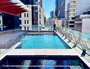 a person standing on top of a building with a swimming pool at Sydney Cosmopolitan CBD Apartment in Sydney