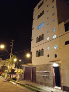 wysoki biały budynek w nocy z światłami ulicznymi w obiekcie EDIFICIO MARIA KIAN w mieście San Bartolo