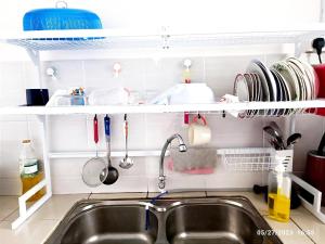 a kitchen sink with utensils and a shelf above it at Homestay Nafisah in Tapah Road