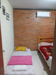 1 dormitorio con 2 camas y pared de ladrillo en Casa em Florianópolis, rio vermelho de 2 quartos bem localizada, en Florianópolis