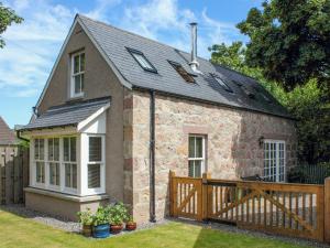 a small stone house with a wooden fence at Sycamore Cottage - Uk45923 in Ballater