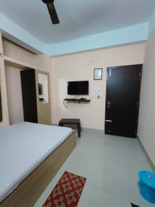 a bedroom with a bed and a flat screen tv at GULAB LODGE in Siliguri