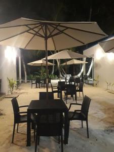 Fulidhoo Hathaa Retreat في فوليدهو: مجموعة طاولات وكراسي مع مظلات