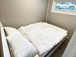 Holiday home Hornnes في Hornnes: سرير أبيض في غرفة مع سيارة في نافذة