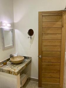 La salle de bains est pourvue d'un lavabo et d'une porte en bois. dans l'établissement PETRAS HOTEL, à Brisas de Zicatela