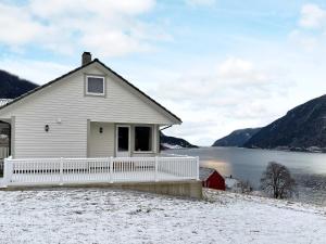 a house with a white fence in front of a lake at Holiday home Ålfoten in Davik