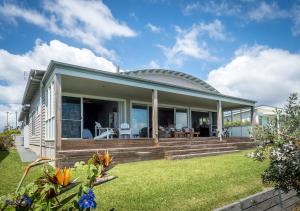 a house with a wrap around porch with a lawn at 'South Pacific' - Luxury Oceanfront at Culburra! in Culburra Beach