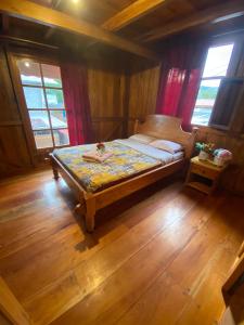 ein Schlafzimmer mit einem Bett in einem Zimmer mit Holzböden in der Unterkunft Chocotulipe Lodge & Spa in Mindo