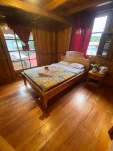 ein kleines Bett in einem Zimmer mit Holzböden und Fenstern in der Unterkunft Chocotulipe Lodge & Spa in Mindo