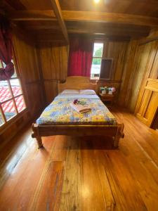 ein Schlafzimmer mit einem Bett in einem Holzzimmer in der Unterkunft Chocotulipe Lodge & Spa in Mindo
