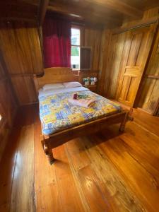 ein kleines Bett in einem Zimmer mit Holzböden in der Unterkunft Chocotulipe Lodge & Spa in Mindo