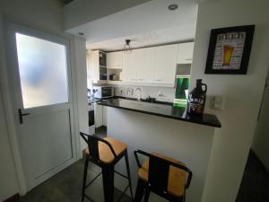 a kitchen with a counter and some chairs in it at Lindo apto Mvd shopping puerto de buceo/pocitos in Montevideo