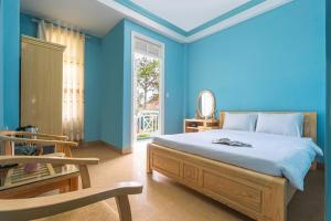 um quarto azul com uma cama e uma cadeira em Kim Long Hotel Đà Lạt em Da Lat