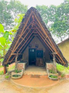 ein Haus mit einem dreieckigen Dach mit einer Tür in der Unterkunft Prana Ayurveda Chalet- Sigiriya in Sigiriya