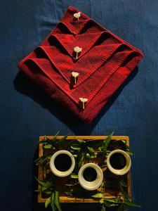 - un plateau en bois avec trois anneaux sur une serviette rouge dans l'établissement Prana Ayurveda Chalet- Sigiriya, à Sigirîya