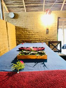 een kamer met een bed met een blauwe deken en bloemen bij Prana Ayurveda Chalet- Sigiriya in Sigiriya