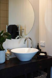 a bathroom with a white sink and a mirror at Quail Run Cottage with stunning vineyard views in Renwick +16 photos