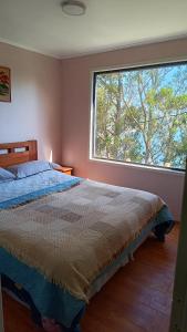 1 dormitorio con cama y ventana grande en Cabañas vista playa San Ignacio, en Valdivia