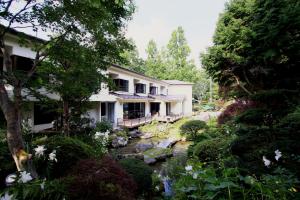 a house with a stream in front of a garden at Teiensaryo Yamanakako in Yamanakako