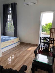 a room with a bed and two chairs and a window at Nhat Long Homestay in Hue