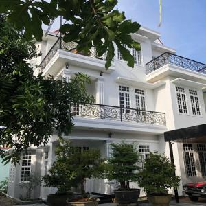 順化的住宿－Nhat Long Homestay，前面有树木的白色建筑