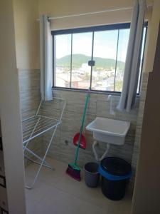 ein Bad mit einem Waschbecken, einem Mopp und einem Fenster in der Unterkunft Selva Park - Apartamentos completos - próximo ao Beto Carrero e praias in Penha