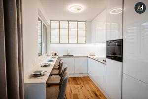 a kitchen with white cabinets and a long table with chairs at Albelli Luxury Skyview in Košice