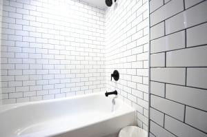 a white bathroom with a tub and white tiles at Mila Downtown Home in Montreal