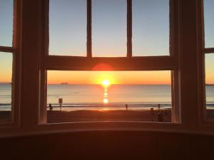 ウェイマスにあるWhitecliff Guest Houseの夕日のビーチを望む窓