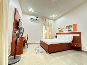 a bedroom with a bed and a fan in it at Asher’s Villa in Garki
