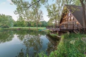 una casa con un ponte accanto a un corpo d'acqua di Secluded Waterfront A-Frame Cabin w/ Pvt Lake a Fithian