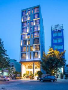a tall building with cars parked in front of it at Hai Trieu Hotel in Da Nang