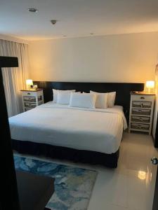 1 dormitorio con 1 cama grande con sábanas y almohadas blancas en The Regent Kamala Penthouse with private pool en Kamala Beach