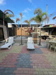 eine Terrasse mit weißen Stühlen, Tischen und Palmen in der Unterkunft Casa Halley #6 con vista al mar in Playas