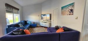 un salon avec des canapés bleus et une télévision dans l'établissement Rye Getaway on Loatta, à Rye