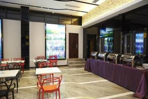 Lavande Hotel Sanya Sanya Bay Jixiang Street في سانيا: غرفة طعام مع طاولات وكراسي حمراء وطاولات ونوافذ