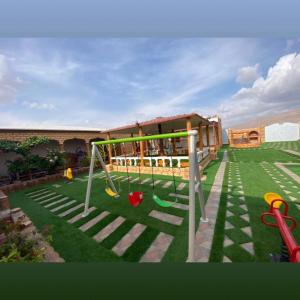 einen Hinterhof mit Spielplatz mit Schaukel in der Unterkunft أستراحة السعادة in Jalan Bani Buhassan