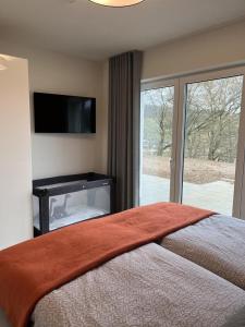 a bedroom with a bed with a flat screen tv at diemelblick acht - Ferienhaus für 6 Personen mit Sauna, Garten und Dachterrasse mit Panoramablick in Heringhausen