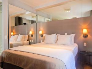 Habitación de hotel con 2 camas y un espejo grande. en Easy Star - Flat Aconchegante C/Vaga na Bela Cintra - XA03G, en São Paulo